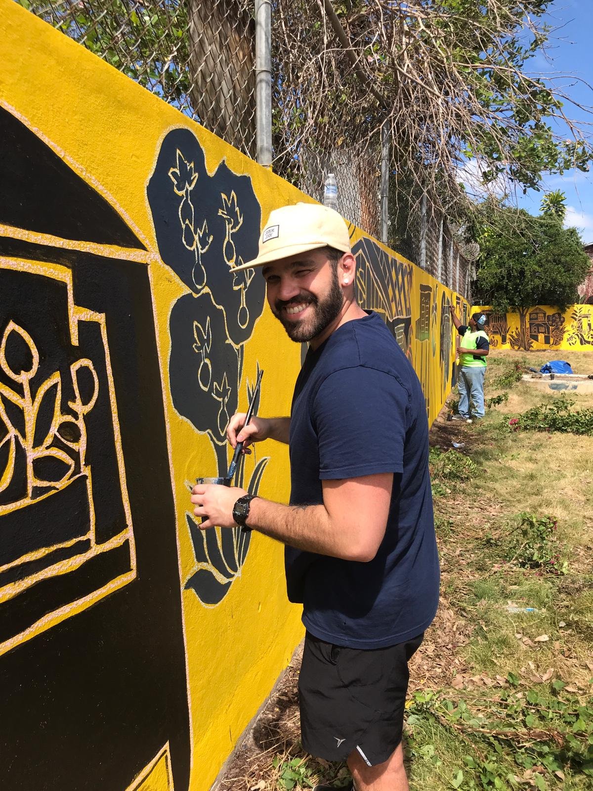  AD&amp;v team member posing for picture while painting mural 