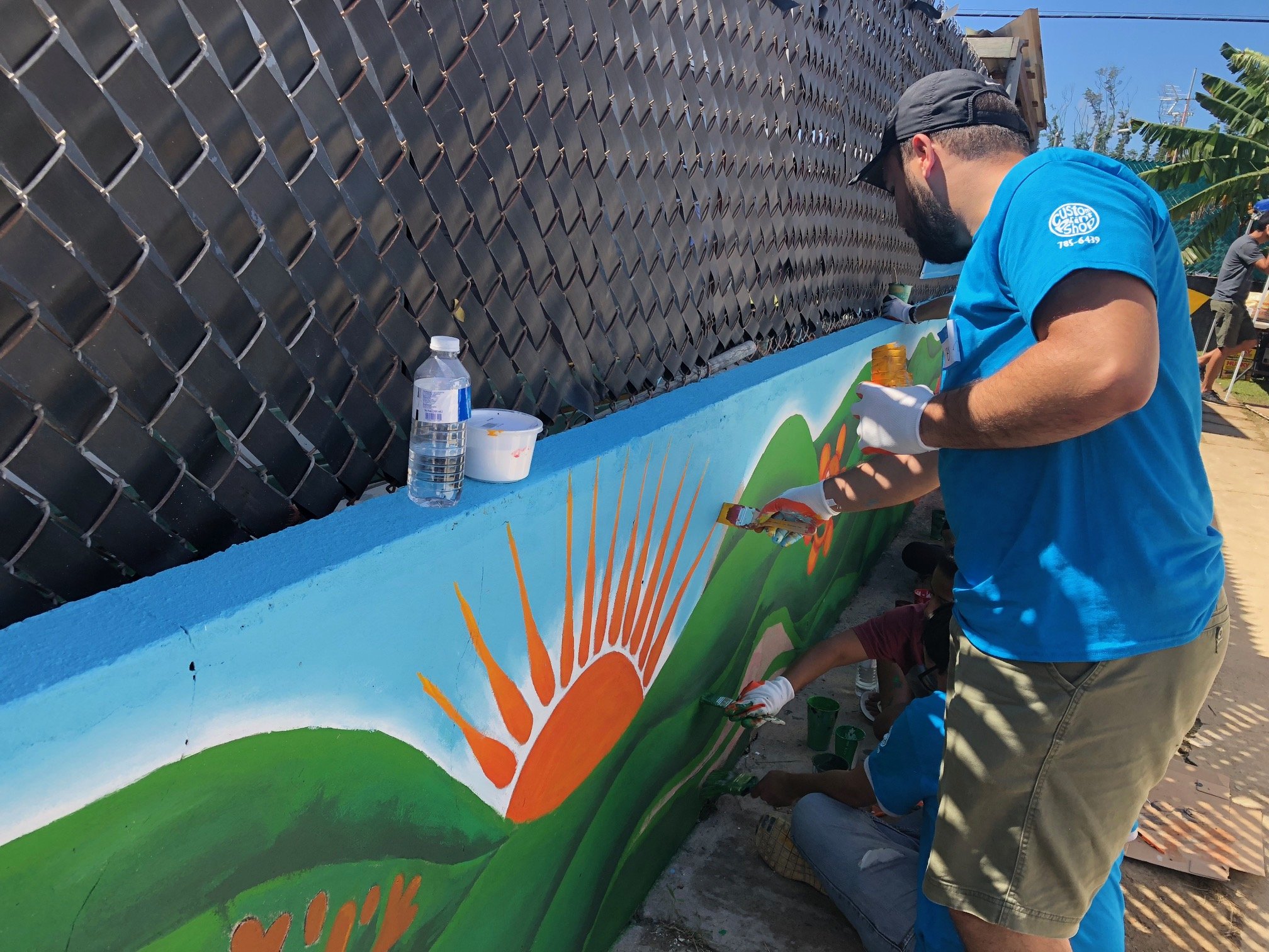  Volunteers painting mural in exterior of home 